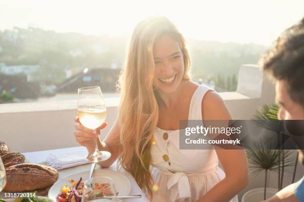 portrait of a couple enjoying a meal with friends outdoors at sunset. - restaurant happy couple stock pictures, royalty-free photos & images