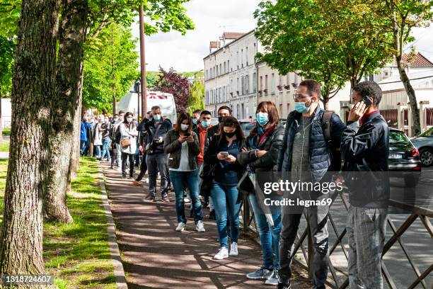 vaccinodrome in france : people waiting for coronavirus vaccination, in the street, in front of the entrance area of covid-19 vaccination center - lining up for vaccine stock pictures, royalty-free photos & images