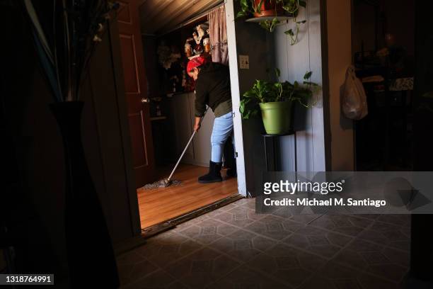 Imelda Valdivia, a farm worker originally from Michoacán, Mexico, mops the front entrance of her home after arriving home from work on May 18, 2021...