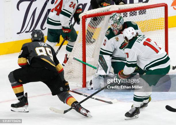 Alex Tuch of the Vegas Golden Knights scores a third-period power-play goal against Cam Talbot of the Minnesota Wild as Marcus Foligno of the Wild...