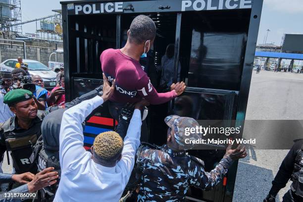 Policemen pushing a protestor into a police van during a demonstration against the re-opening of the Lekki toll plaza in Lagos. Activists had called...