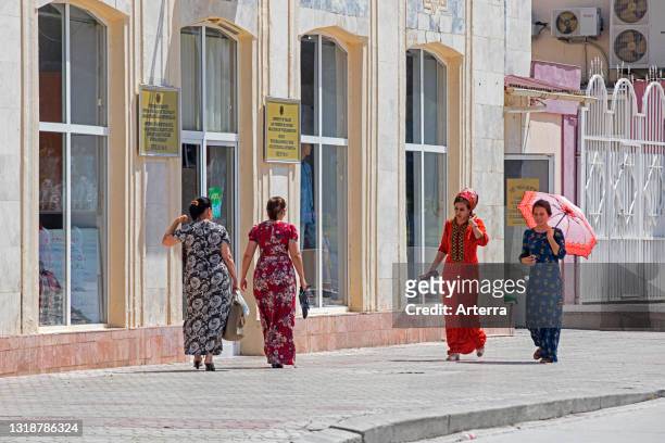 Turkmen women walking on pavement wearing a koynek, traditional long dress with embroidery in the capital city Ashgabat, Turkmenistan.