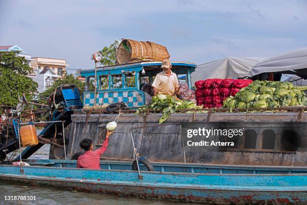 Vietnamese farmer selling vegetables from traditional wooden boat at the floating market of the city Can Tho in the Mekong Delta, Vietnam.