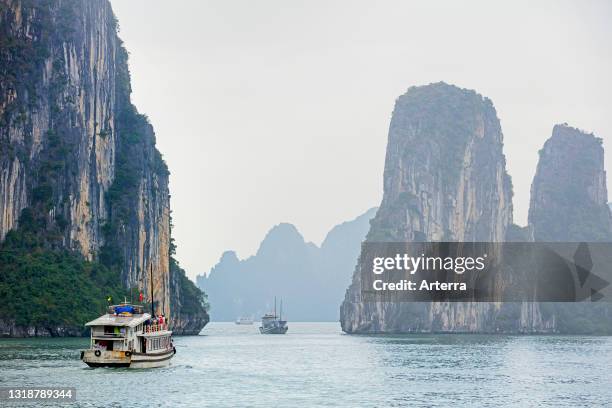 Tourist boats and limestone monolithic islands in Ha Long Bay / Halong Bay / Vinh Ha Long in the mist, Quang Ninh Province, Vietnam.