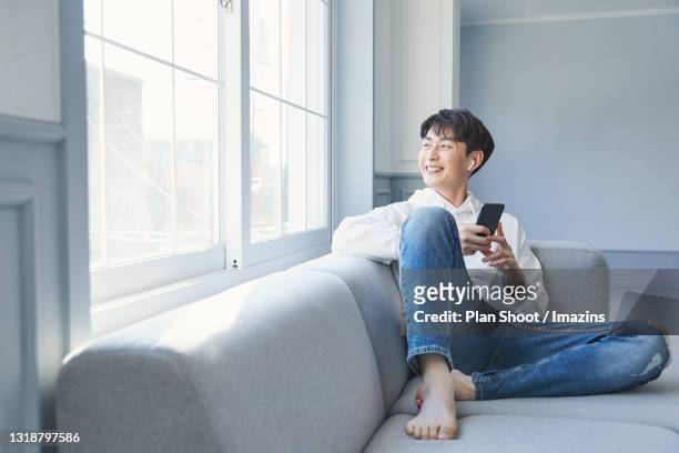a man using audio application through smartphone - asian man barefoot foto e immagini stock