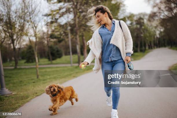 mooie jonge vrouw die met hond in park op zonnige de lentedag loopt - running in park stockfoto's en -beelden