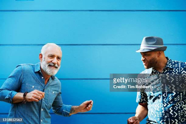 two men dancing in front of blue wall - baby boomer millennial stock pictures, royalty-free photos & images