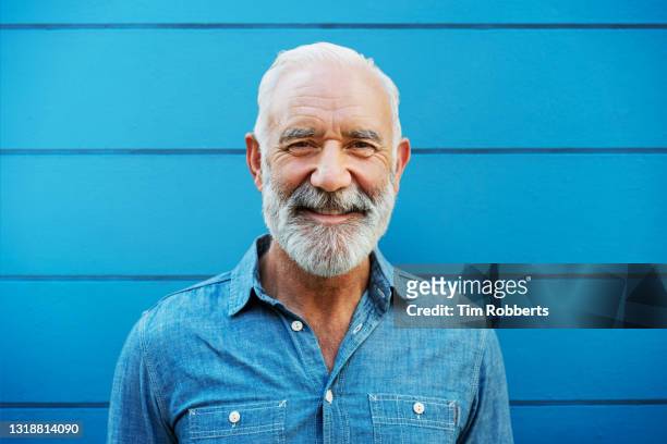 portrait of man in front of blue wall - old hipster stock-fotos und bilder