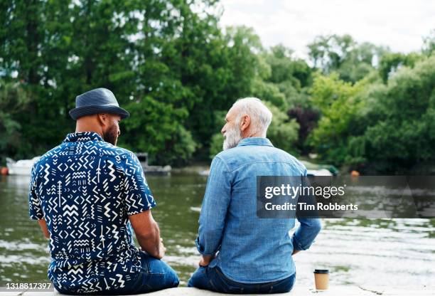 two men having conversation next to river - friends serious stock pictures, royalty-free photos & images