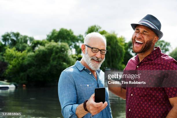 two men laughing with smart phone - european best pictures of the day october 17 2017 stockfoto's en -beelden