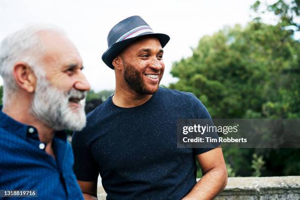 two men looking off camera, smiling - man smile very casual relaxed authentic outdoor stock pictures, royalty-free photos & images