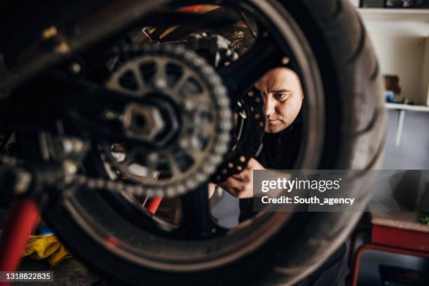 mechanic repairing motorcycle - motorcycle mechanic stock pictures, royalty-free photos & images