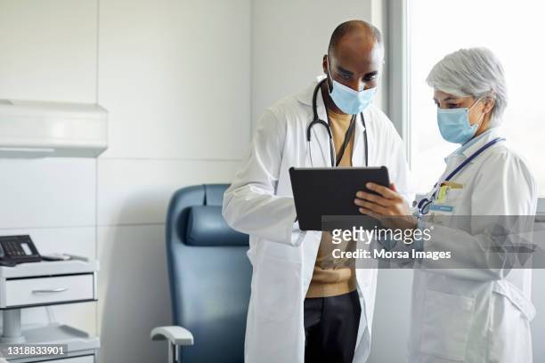 medical workers with digital tablet in hospital - doctor mask stock-fotos und bilder