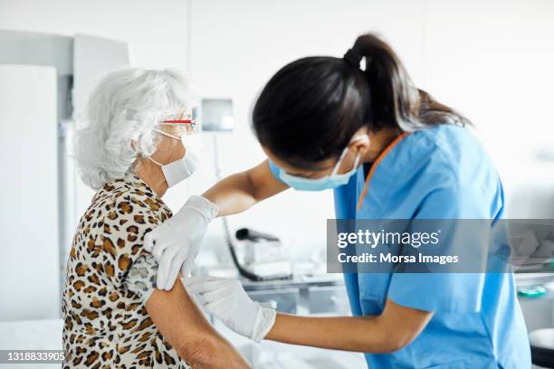 nurse injecting on arm of patient in hospital - protective face mask side stock pictures, royalty-free photos & images