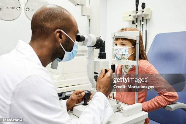 ophthalmologist examining girl's eye in hospital - infectious disease prevention stock pictures, royalty-free photos & images