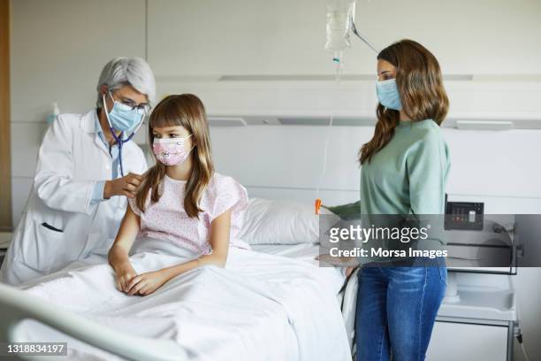 doctor examining patient by mother in hospital - covid-19 patient stock pictures, royalty-free photos & images