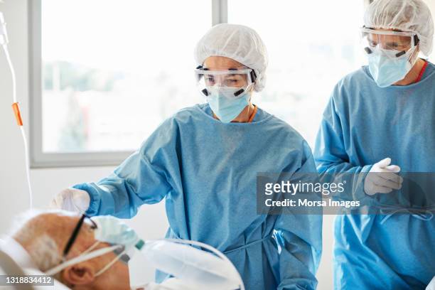 doctors examining patient in ward during covid-19 - respiratory machine stock-fotos und bilder