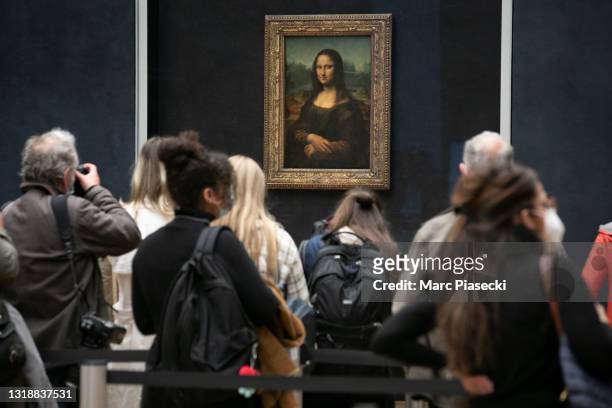 Visitors observe the painting 'La Joconde' The Mona Lisa by Italian artist Leonardo Da Vinci on display in a gallery at Louvre on May 19, 2021 in...