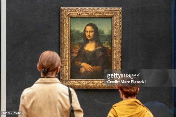 Visitors observe the painting 'La Joconde' The Mona Lisa by Italian artist Leonardo Da Vinci on display in a gallery at Louvre on May 19, 2021 in...
