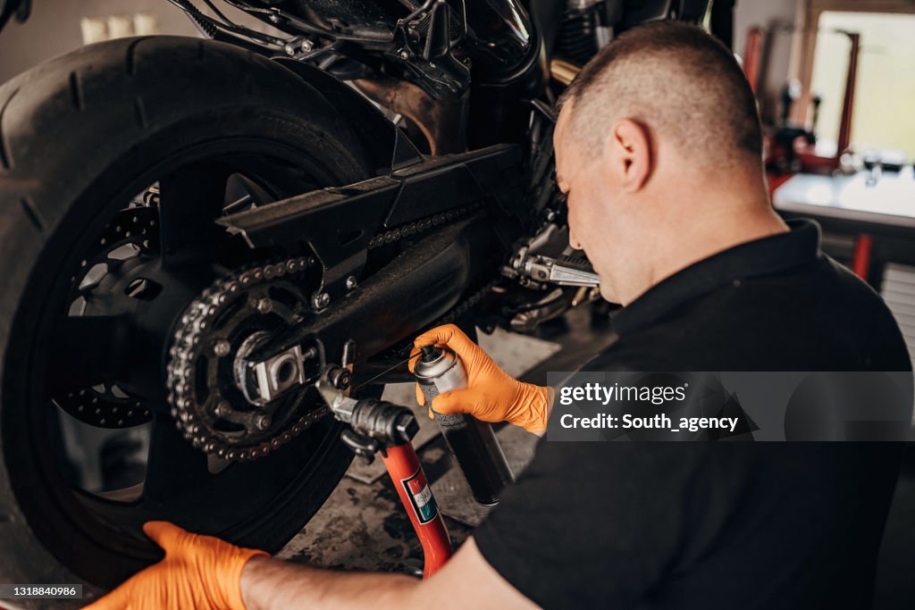 Male mechanic repairing motorcycle chain