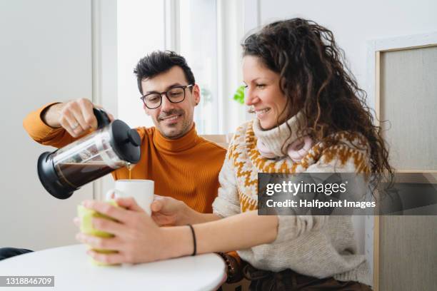 young couple with coffee moving in new home, relocation concept. - coffee plunger stock pictures, royalty-free photos & images