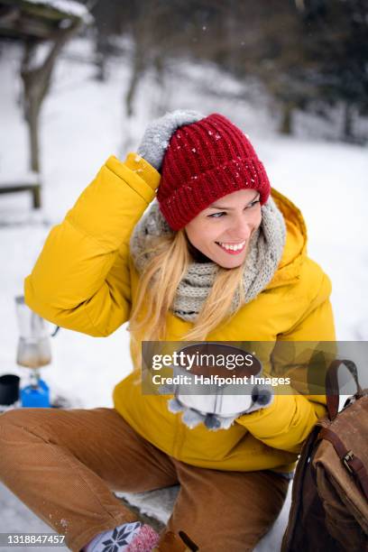 mid adult woman in winter nature, eating soup made on camping stove. - hot beverage stock-fotos und bilder