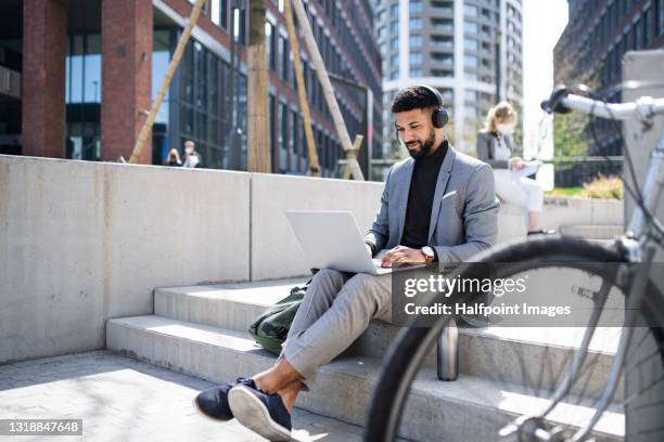 portrait of man commuter with bicycle using laptop in city. - business outdoor stock-fotos und bilder