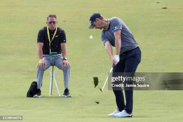 Justin Rose of England plays a shot on the tenth hole as golf instructor Sean Foley looks on during a practice round prior to the 2021 PGA...