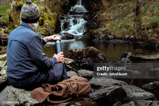 senior man with a thermos flask at a waterfall - forest bathing stock pictures, royalty-free photos & images