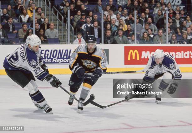 Ian Laperriere, Right Wing and Eric Belanger, Center for the Los Angeles Kings challenge Cliff Ronning of the Nashville Predators for the puck during...