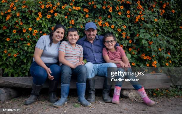 glückliche lateinamerikanische familie sitzt auf einer bank auf dem bauernhof - latin father and son stock-fotos und bilder