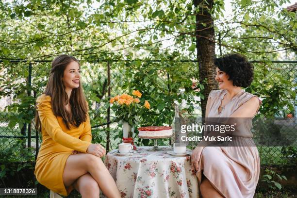 two women looking each other smiling during the tea party - tea party stock pictures, royalty-free photos & images