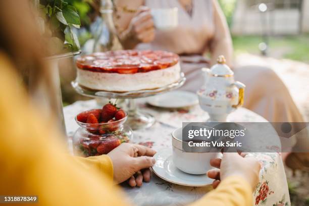 femme tenant une tasse de thé sur la table de jardin - goûter photos et images de collection