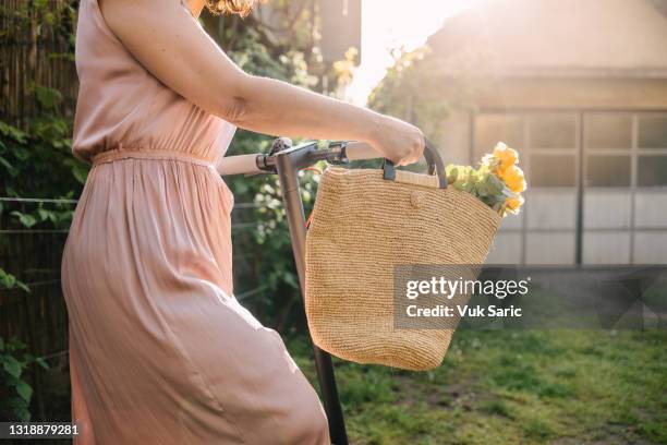 woman pushing an electric scooter - woman sleeveless dress stock pictures, royalty-free photos & images