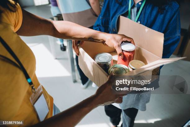 close up photo of volunteers preparing donation boxes with food at the food and clothes bank - homeless shelter stock pictures, royalty-free photos & images