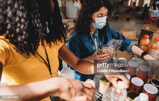 twee vrouwen schikken voedsel en dranken op de planken - sluit omhoog ontsproten - food pantry stockfoto's en -beelden