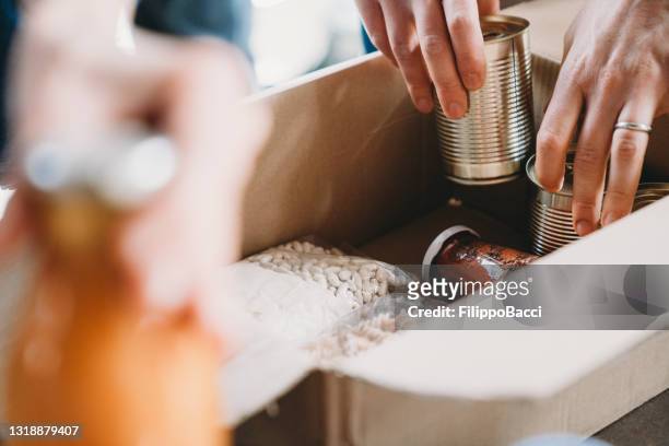 close up photo of volunteers preparing donation boxes with food at the food and clothes bank - donation box stock pictures, royalty-free photos & images