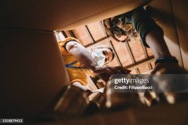 volunteers are preparing a donation box with nonperishable food - view from inside the cardboard box - ngo imagens e fotografias de stock