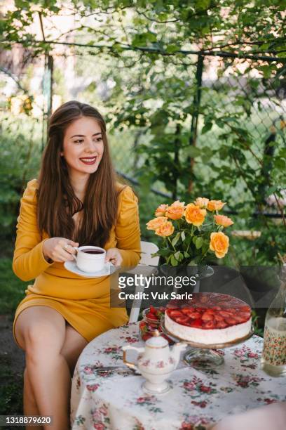 woman holding a teacup tea in the garden - cake party stock pictures, royalty-free photos & images