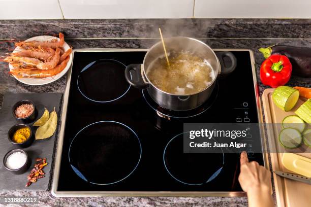 woman preparing food on modern cooktop - electric stove burner ストックフォトと画像