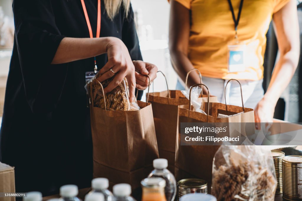 Foto ravvicinata di volontari che preparano borse di donazione con cibo alla banca del cibo e dei vestiti