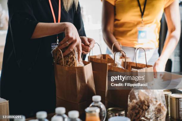 close up photo of volunteers preparing donation bags with food at the food and clothes bank - food donation stock pictures, royalty-free photos & images