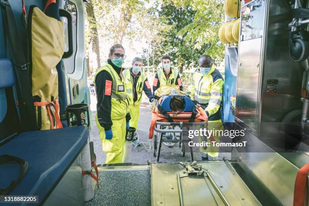 emergency rescue team carrying a patient up in ambulance - red cross stock pictures, royalty-free photos & images