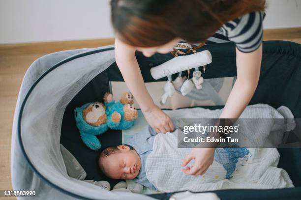 asian chinese young mothe rtapping her infant baby boy in crib in bedroom - baby goods stock pictures, royalty-free photos & images