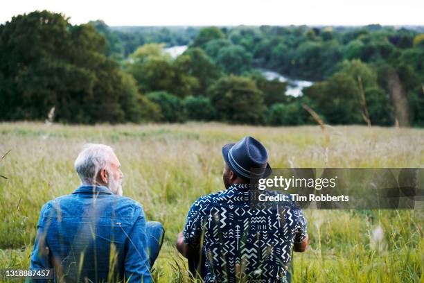 two men sat, talking, looking at view - amigos charlando fotografías e imágenes de stock