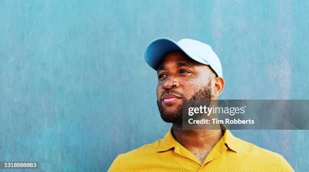 man in baseball cap looking off camera - confident looking to camera stock-fotos und bilder