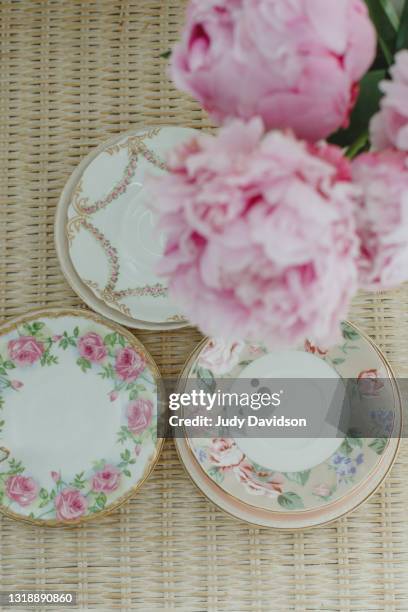 collection of vintage floral plates on a yellow wicker table with pink peonies - mismatch 個照片及圖片檔