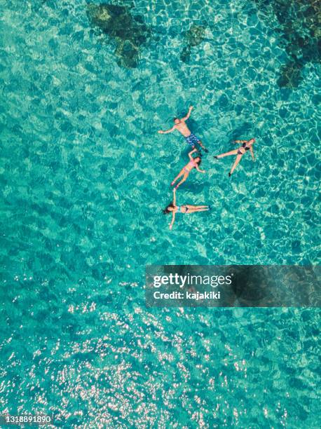 luftaufnahme einer jungen familie, die am schönen strand auf der griechischen insel schwimmt und schwimmt - ägäisches meer stock-fotos und bilder