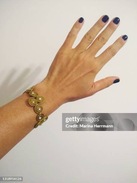 female hand with bracelet - gold nail polish stock-fotos und bilder