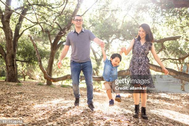 family with child walking in the park holding hands - young family outside stock pictures, royalty-free photos & images